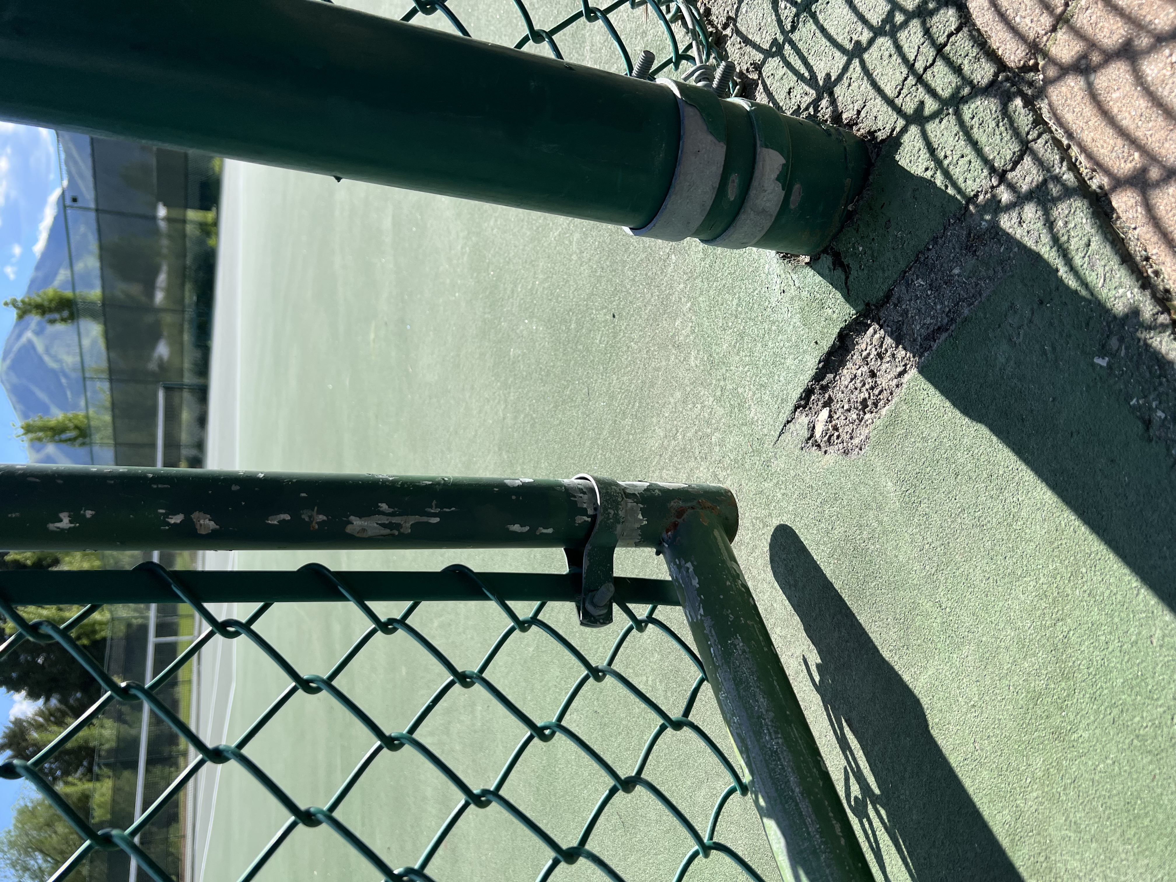 Cracked and chipped court surface at the base of a gate post