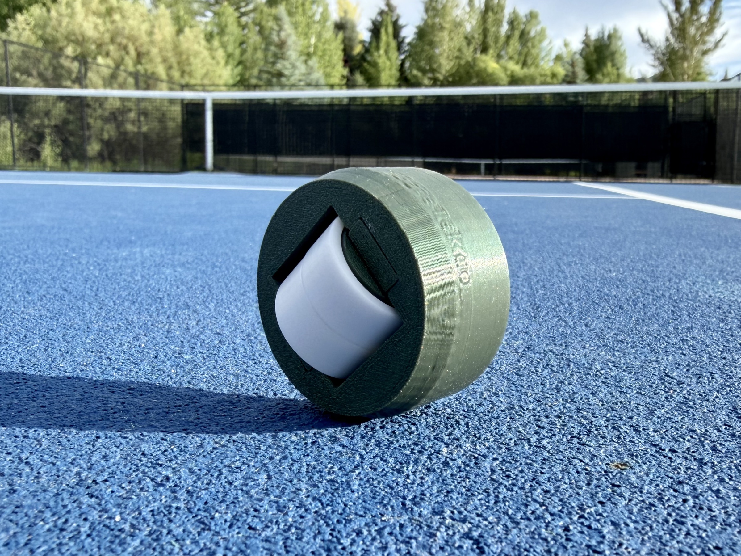 GateTek cap resting on a blue tennis court, internal caster wheel visible