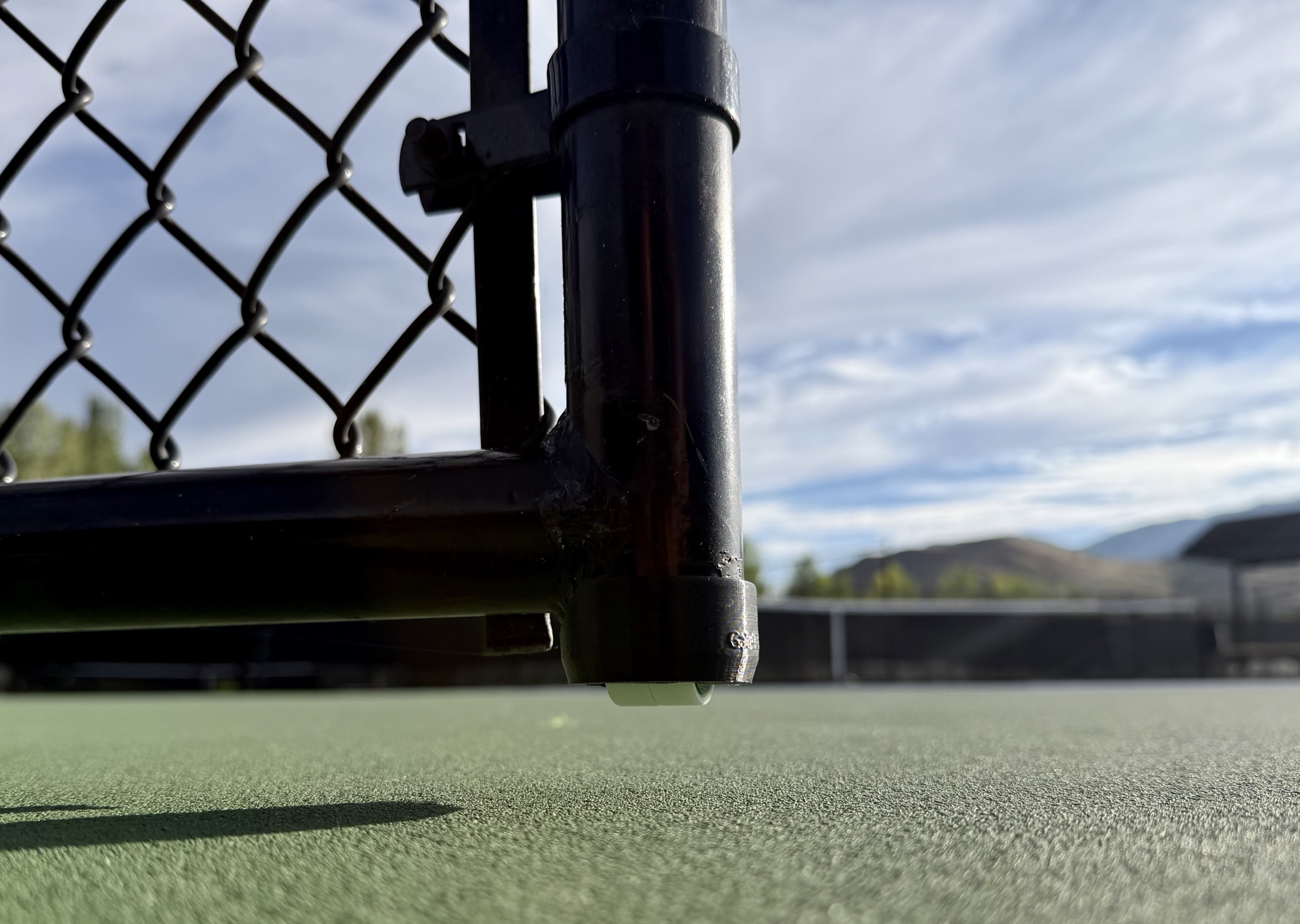 GateTek cap installed on the same gate post, wheel resting on the court